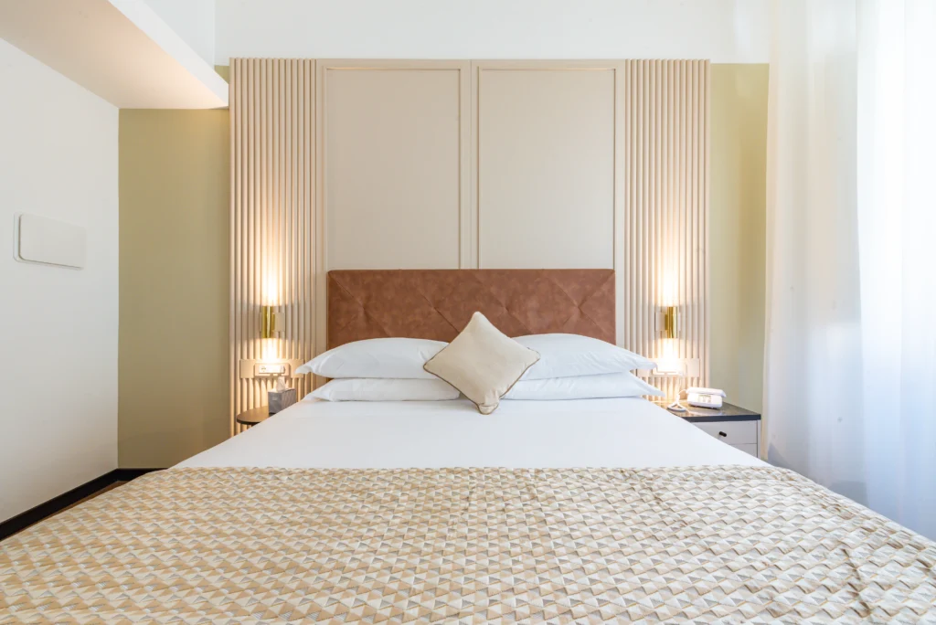 primo piano di un letto matrimoniale. La parete e le lampade ai lati del letto danno un'aria molto elegante alla stanza